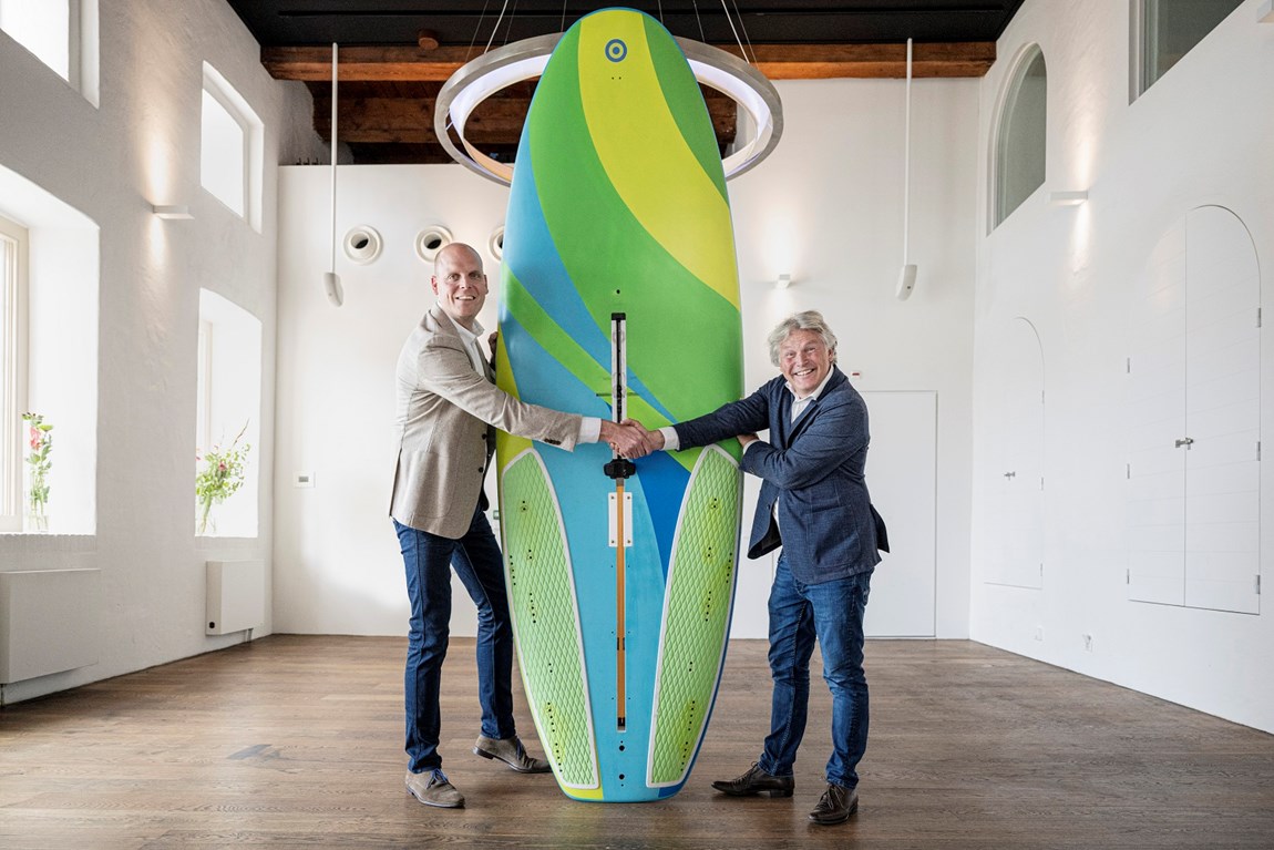 Arno van Gerven (links), directeur van het Watersportverbond en Michael Huijser, directeur Scheepvaarmuseum met het RS:X board waarop Dorian van Rijsselberghe in 2016 goud behaalde op de Olympische Spelen in Rio. 