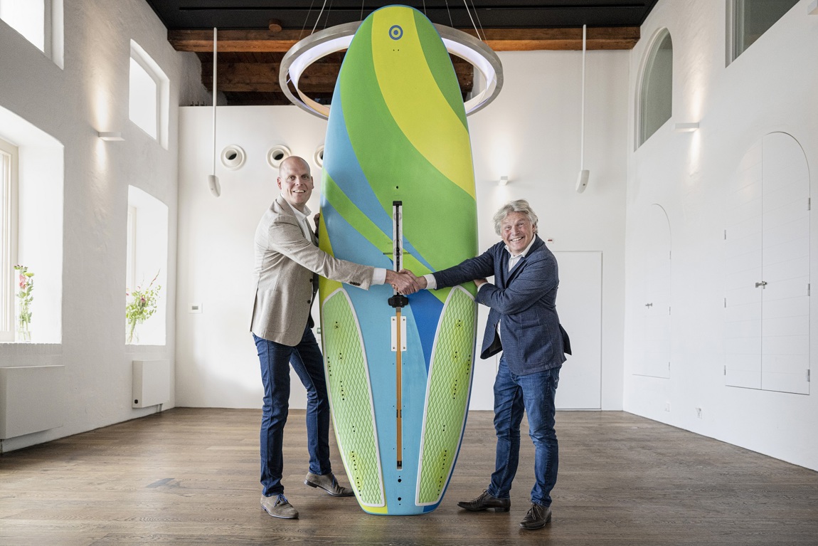 Arno van Gerven (links), directeur van het Watersportverbond en Michael Huijser, directeur Scheepvaarmuseum met het RS:X board waarop Dorian van Rijsselberghe in 2016 goud behaalde op de Olympische Spelen in Rio. 
